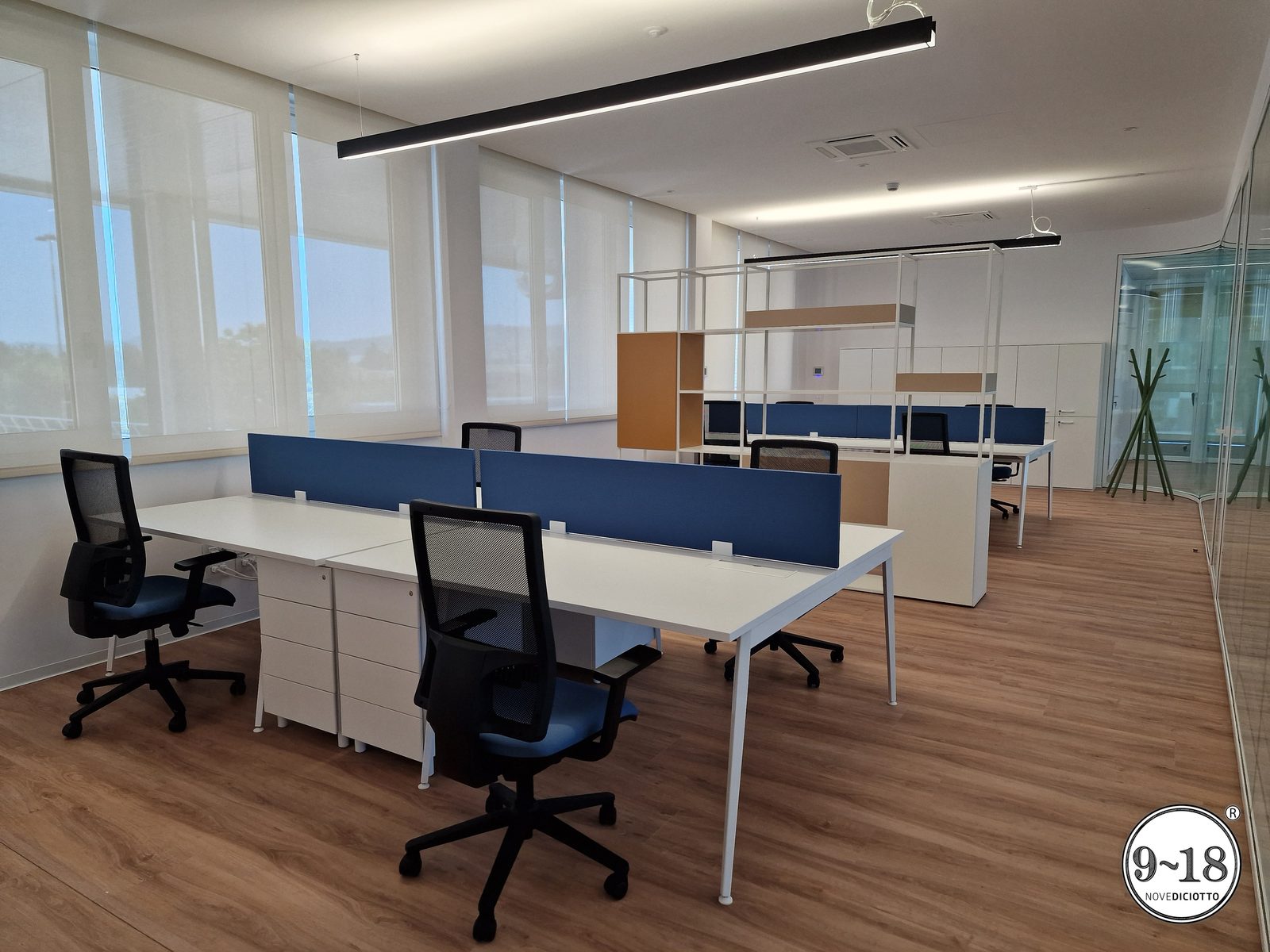 Open space operativo con postazioni, schermi divisori e ampie vetrate.